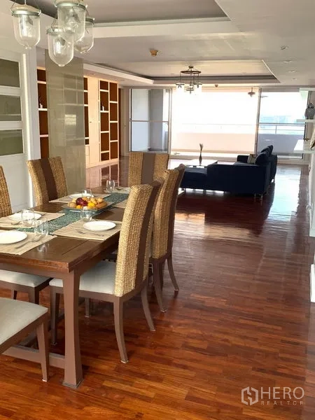 Condominium for sale in Khlong Toei, Bangkok - Dining area with an eight-seat table and rattan chairs overlooking the living space.