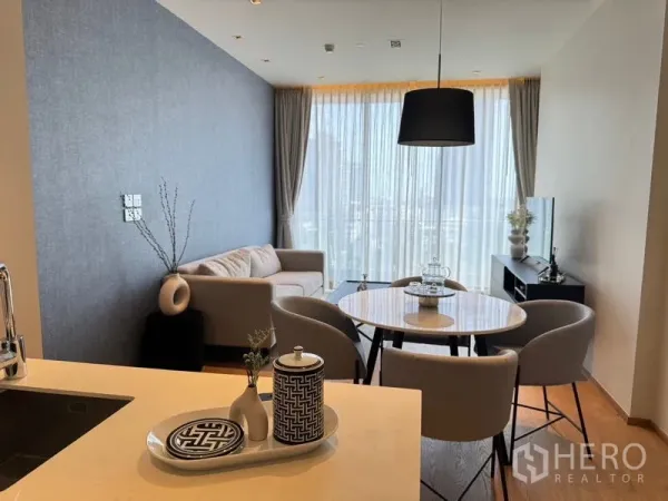 Condominium for rent - Bright living and dining area with round table, sofa, and floor-to-ceiling sheer curtains.
