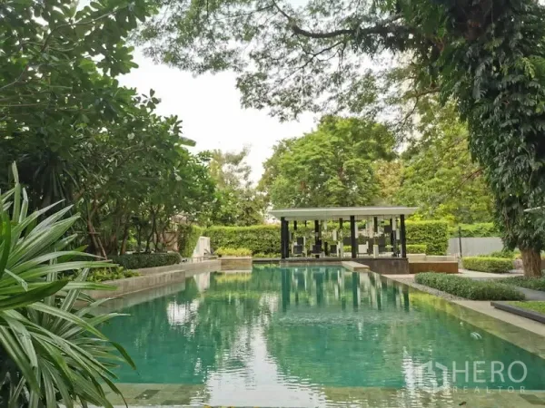 Condominium for rent in Watthana, Bangkok - Resort-style outdoor swimming pool surrounded by lush gardens and a pavilion.