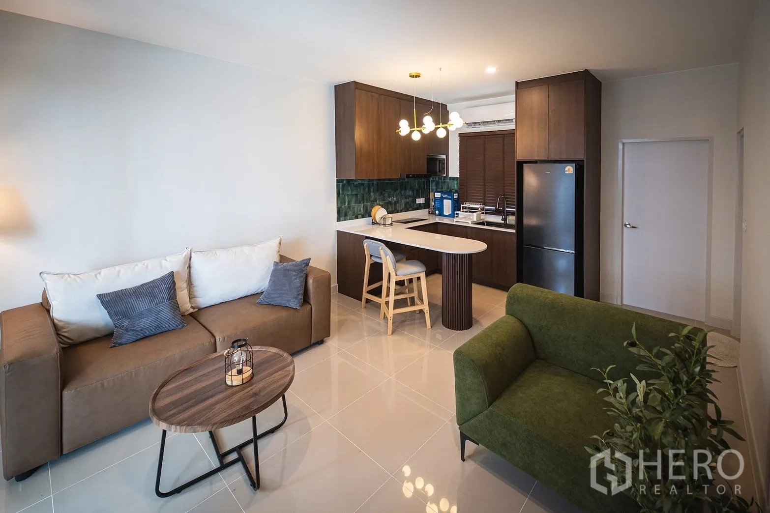 Townhouse for rent in Bang Phli, Samut Prakan - Open-plan living area with sofas and a modern kitchen with island counter.