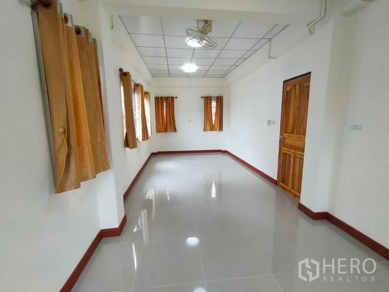 Detached House for rent in Khlong Toei, Bangkok - Long airy room with polished floor, side windows and a wooden interior door.