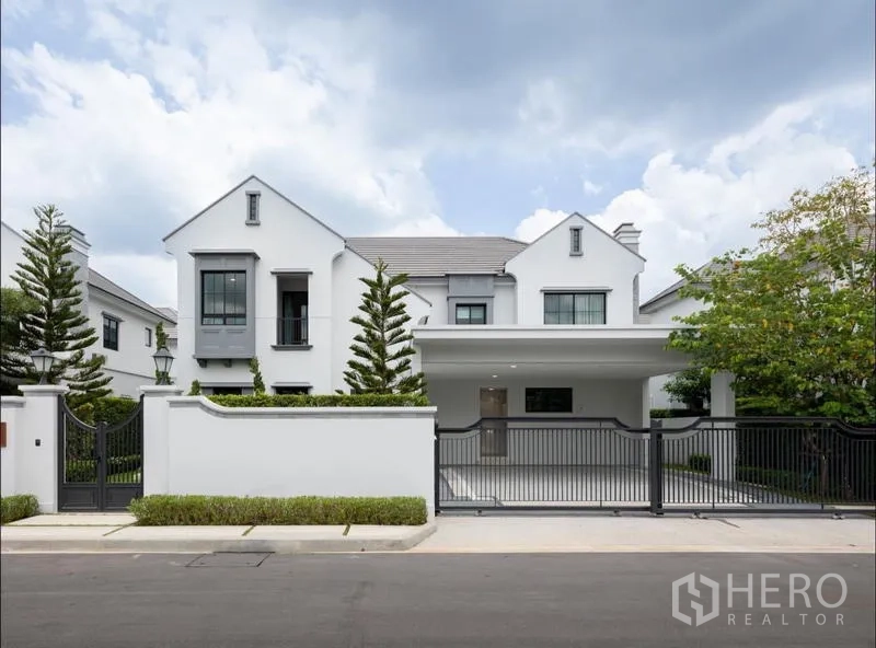 Detached House for sale in Saphan Sung, Bangkok - Modern two-storey white detached house with gated entrance and driveway.