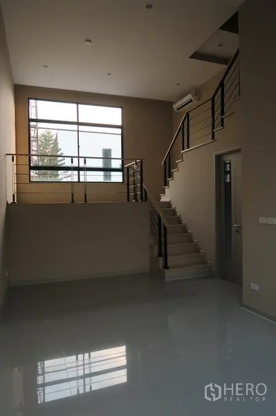 Townhouse for rent in Suan Luang, Bangkok - Mezzanine-style living space with staircase, metal railings, and a large window.