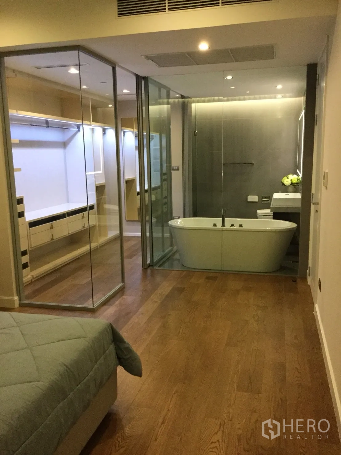 Condominium for rent in Sathon, Bangkok - Master bedroom with walk-in closet and a glass-walled bathroom showcasing a freestanding bathtub.