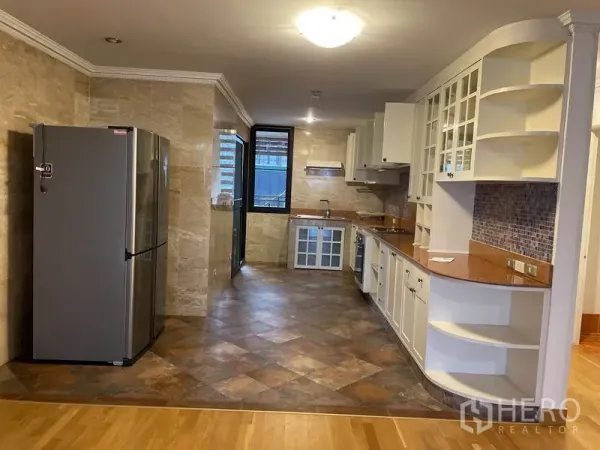 Condominium for rent in Watthana, Bangkok - Long galley kitchen with white cabinetry, mosaic backsplash and a built-in oven beside a window.