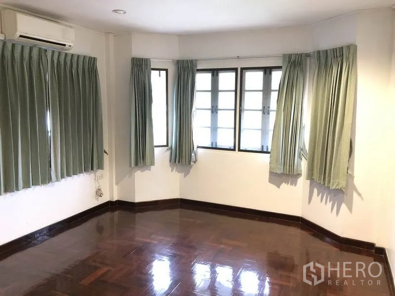 บ้าน ให้เช่า - ห้องนอนมุมบ้านมีหน้าต่างแบบเบย์วินโดว์และผ้าม่านสีเขียว