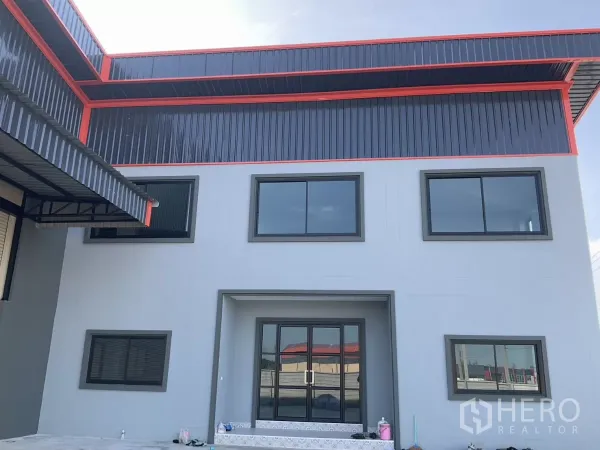 Factory for sale in Samut Sakhon - Front facade close-up showing the office entrance with large windows beneath a steel awning.