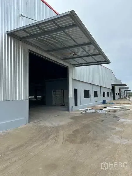 Factory for rent in Rayong - Modern factory exterior with large loading bay, metal canopy and wide concrete driveway in Nikhom Phatthana, Rayong.
