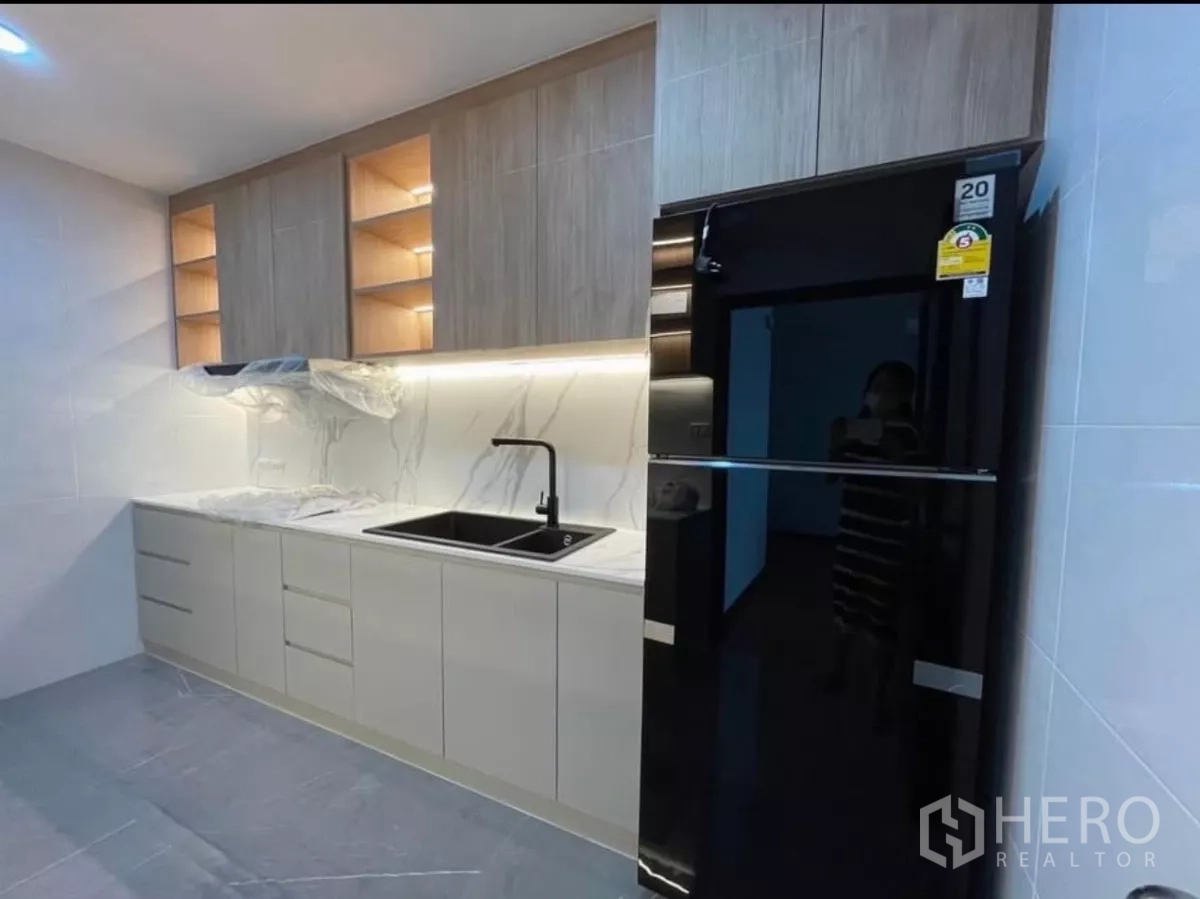 Condominium for rent in Sathon, Bangkok - Kitchen run with twin sinks, light cabinetry, and black refrigerator.