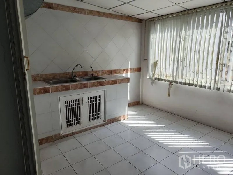 Shophouse for sale in Pathum Thani - Bright tiled pantry with double sink and large window with blinds.
