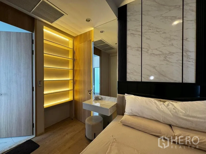 公寓 出租在Watthana, Bangkok - 卧室一角，背光置物架、大理石特色墙与梳妆台。