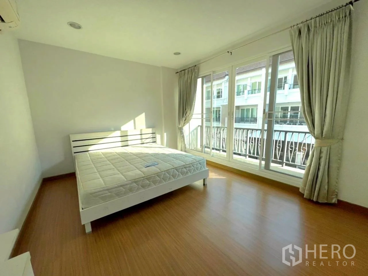 Townhouse for rent in Bang Kho Laem, Bangkok - Large bedroom with bed and floor-to-ceiling sliding windows opening to a balcony.