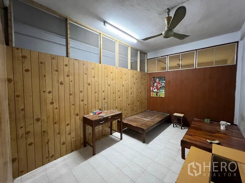 Shophouse for sale in Phra Khanong, Bangkok - Partitioned room with wood panel walls, ceiling fan and simple furniture.