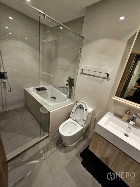 Condominium for rent - Bright bathroom with bathtub, glass shower screen, vanity and tile walls.