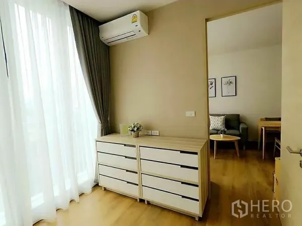 Condominium for rent in Khlong Toei, Bangkok - Corner with twin dressers, floor-to-ceiling sheer curtains and wall-mounted air conditioner.