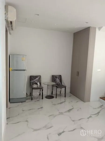 Townhouse for rent in Yan Nawa, Bangkok - Corner nook with refrigerator, two chairs and a built‑in wardrobe.