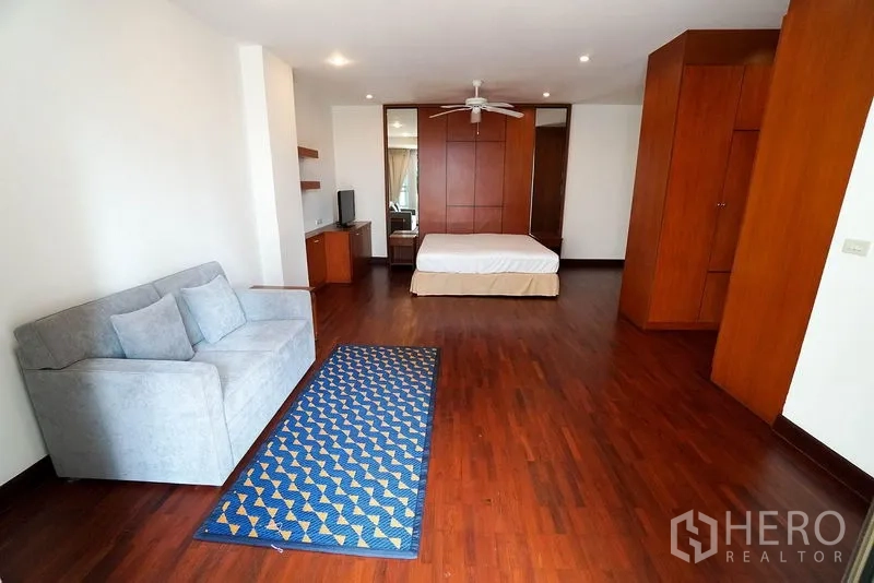 Apartment for rent in Watthana, Bangkok - Oversized master bedroom with wooden floors, sofa corner and built-in wardrobes.