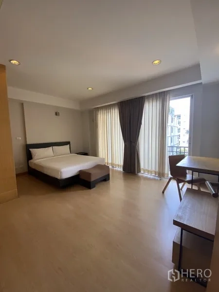 房间 出租在Watthana, Bangkok - 卧室配双人床、书桌及通往阳台的推拉玻璃门。