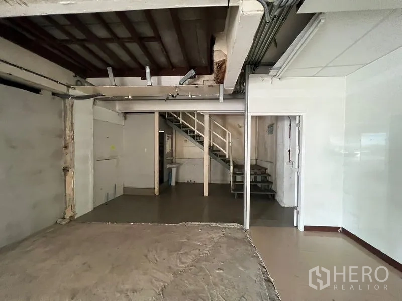 Shophouse for rent in Watthana, Bangkok - Open-plan shop space with back room and staircase access.