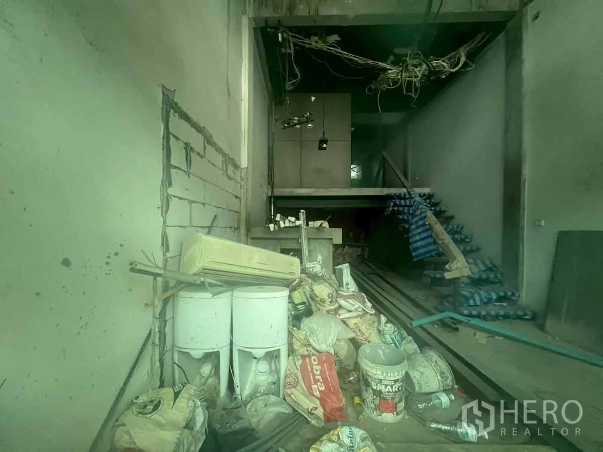 Shophouse for sale - Ground-floor interior in shell condition with construction materials, exposed wiring, and a partial mezzanine.