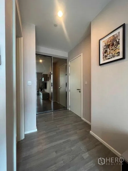 Condominium for rent in Khlong Toei, Bangkok - Bright hallway with wood flooring and mirrored closet doors.