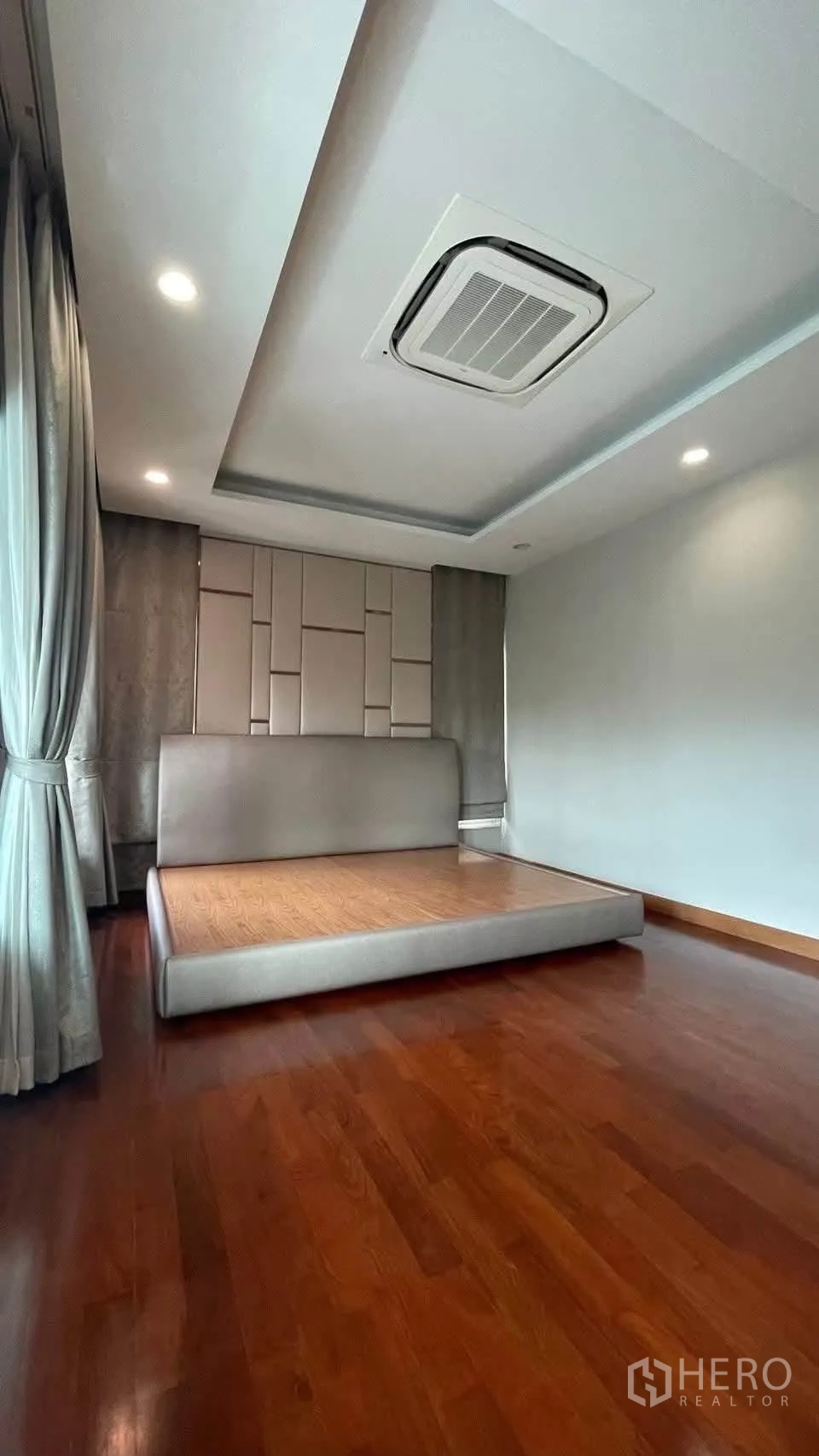 Detached House for rent in Prawet, Bangkok - Primary bedroom with padded headboard, platform bed and wood floors.