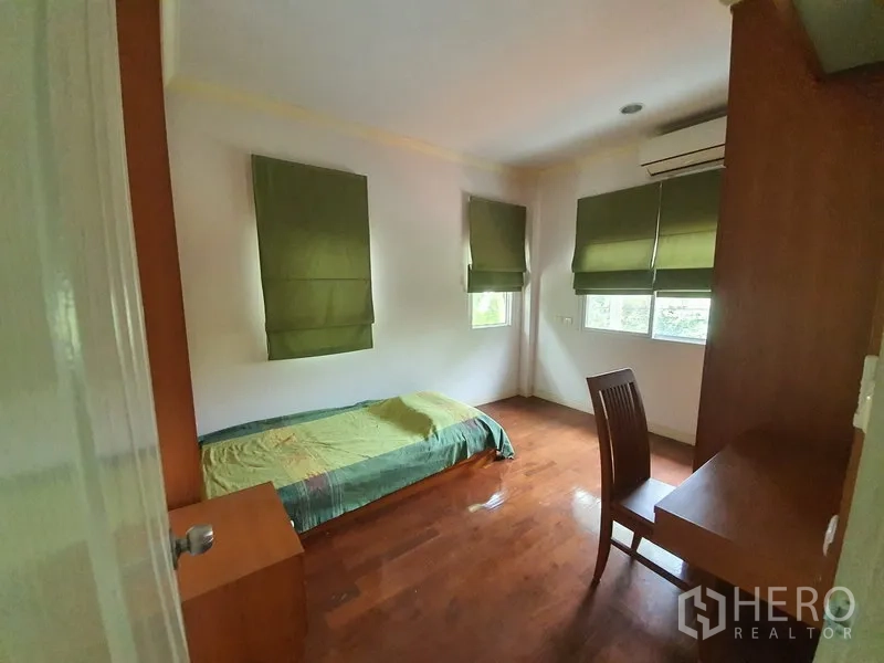 独立式住宅 出租在Lat Krabang, Bangkok - 温馨次卧，木地板，书桌，转角窗配绿色遮光帘。