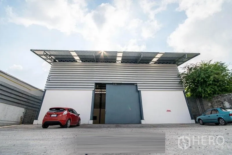 Warehouse for rent - Modern warehouse facade with large blue sliding door and on-site parking.