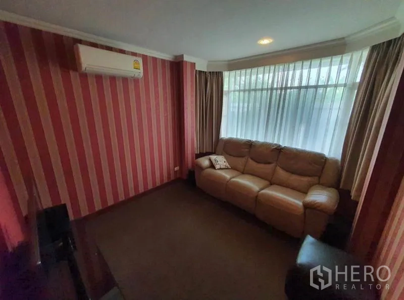 Detached House for sale in Sai Mai, Bangkok - Compact TV lounge with striped feature wall, large window and leather sofa.