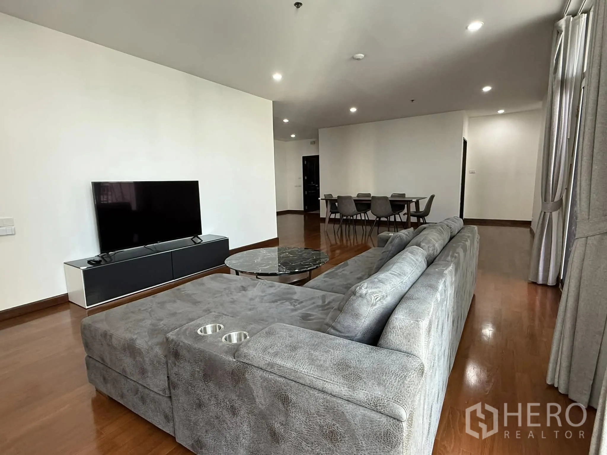 คอนโด for rent in Pathum Wan, Bangkok - ห้องนั่งเล่นมีโซฟาตัวแอลสีเทา ชั้นวางทีวี และโต๊ะกลางหินอ่อน.