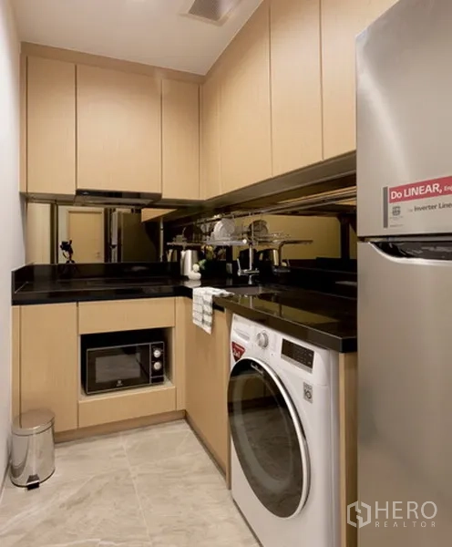 Condominium for rent or sale in Watthana, Bangkok - Compact modern kitchen with built-in cabinets, black countertops and washer.