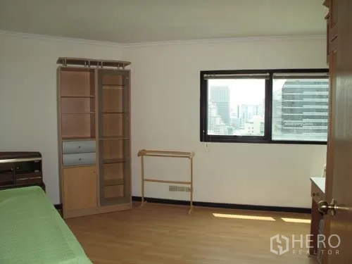 Condominium for rent in Sathon, Bangkok - Second bedroom with window, shelving unit and urban view.