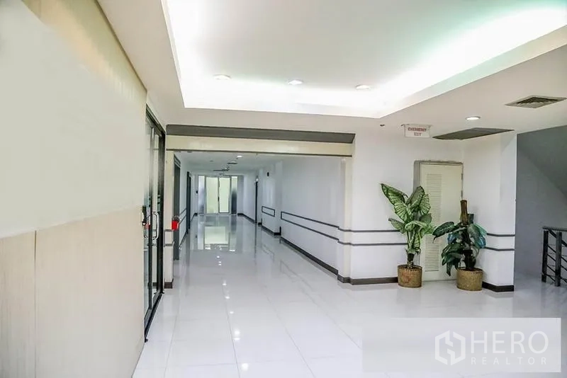 办公空间 出租在Bang Na, Bangkok - 整洁的大厅走道，明亮顶灯与盆栽、玻璃入口。