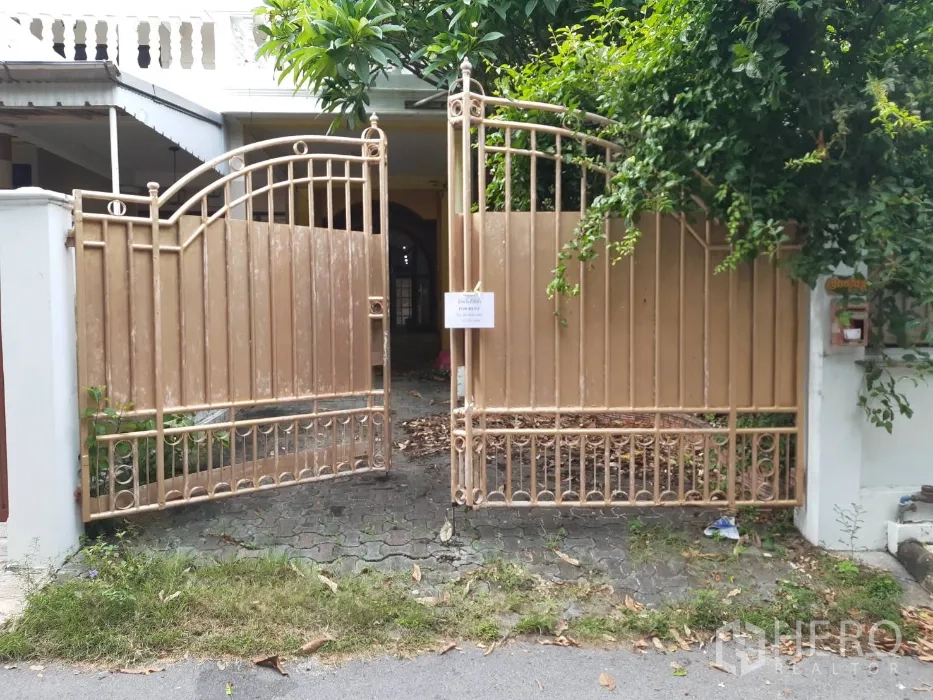 联排别墅 出租在Khlong Toei, Bangkok - 金色金属大门与绿植掩映的联排别墅入口，前方为车道。