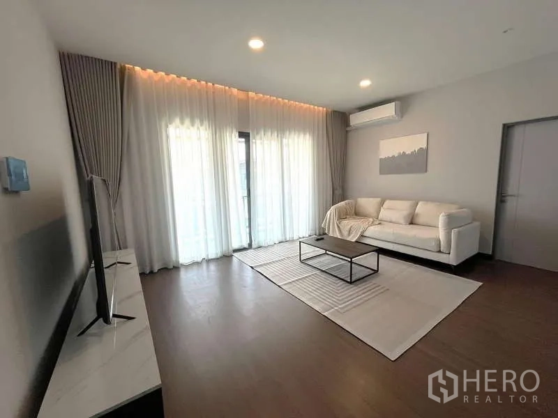 บ้าน ให้เช่าหรือขายในBang Phli, Samut Prakan - ห้องนั่งเล่นชั้นบนพร้อมโซฟา ทีวี และม่านโปร่งเปิดออกสู่ระเบียง