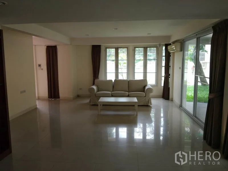独立式住宅 出租在Watthana, Bangkok - 采光良好的客厅，沙发与茶几，推拉门通向花园