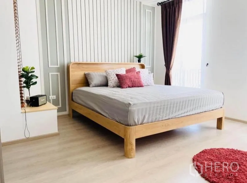 Townhouse for rent in Prawet, Bangkok - Spacious bedroom with wood bed, striped wall panels and balcony light.