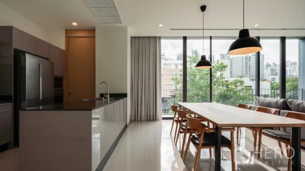 公寓 出租在Bang Kapi, Bangkok - 开放式厨房与餐区，落地窗与吊灯，眺望城市与绿景。