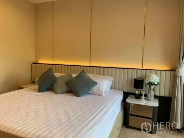 公寓 出租在Pathum Wan, Bangkok - 温馨卧室，软包床头，床头柜、台灯与柔和氛围灯。