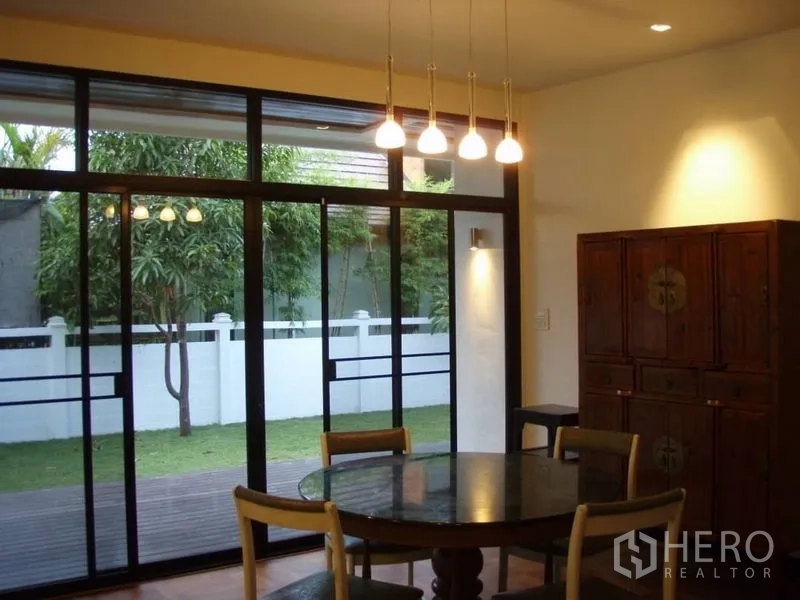 บ้าน ให้เช่าในHuai Khwang, Bangkok - ห้องทานอาหารมองเห็นระเบียงและสนามหญ้าผ่านประตูกระจกบานใหญ่