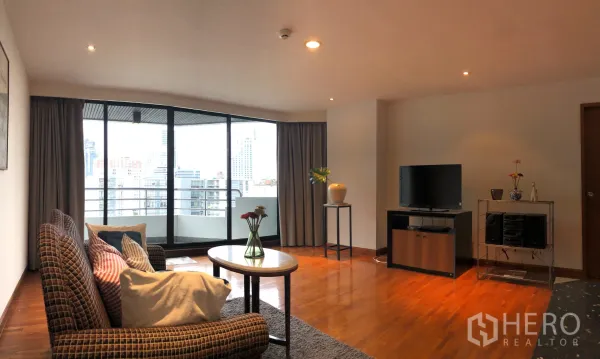 Condominium for rent in Khlong Toei, Bangkok - Living area with full-height sliding doors to the balcony, TV unit and coffee table.