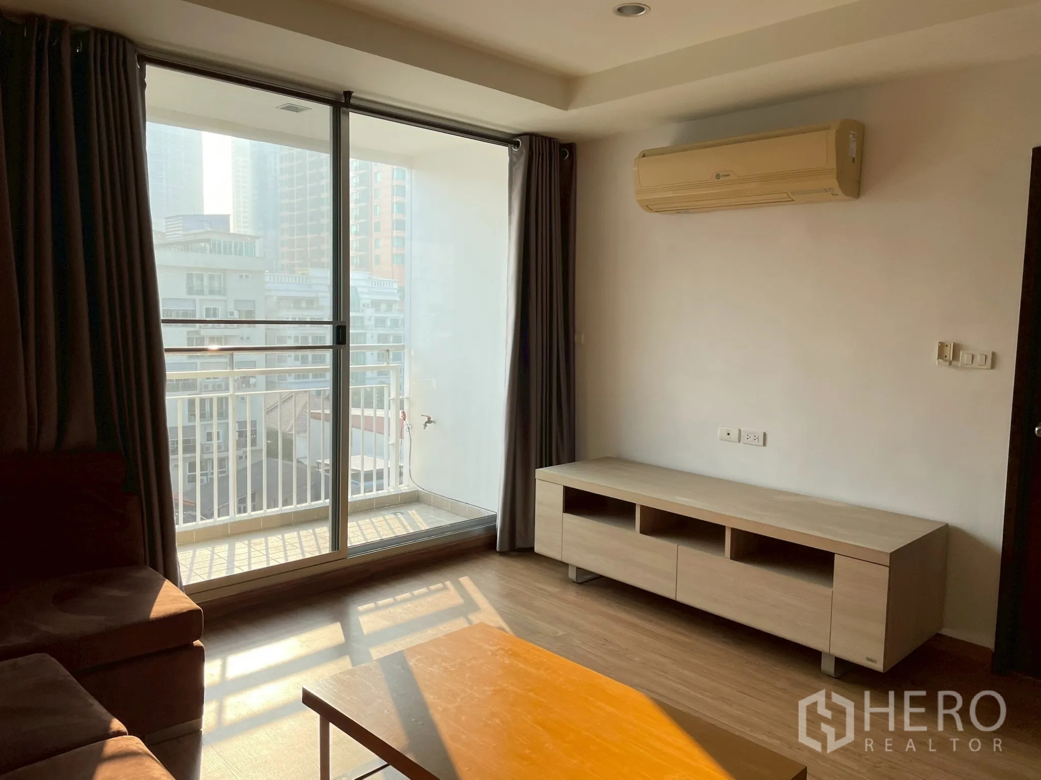 อพาร์ทเมนท์ for rent in Khlong Toei, Bangkok - ห้องนั่งเล่นมีประตูระเบียง เครื่องปรับอากาศติดผนัง และชั้นวางทีวี