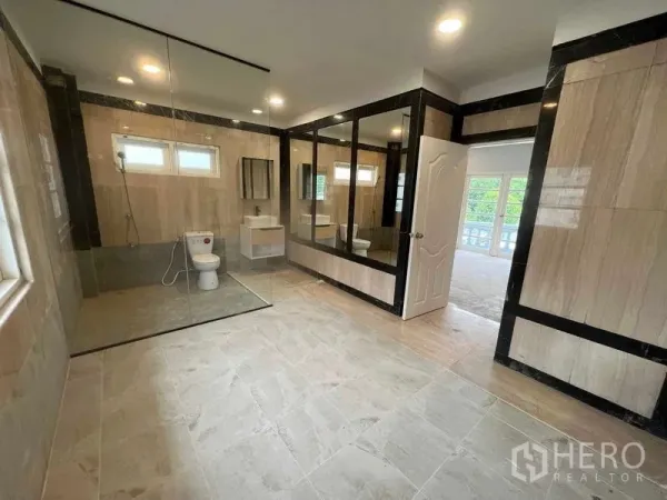 บ้าน ขายในBang Na, Bangkok - ห้องน้ำกว้างพร้อมฉากกั้นกระจก โถสุขภัณฑ์ และอ่างล้างหน้า กรุลายหินโทนเบจดำ