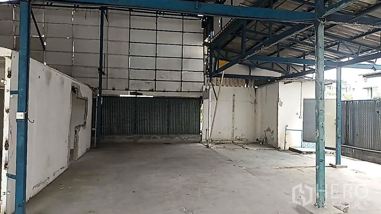 Warehouse for rent in Lat Phrao, Bangkok - Interior warehouse space with concrete floor, corrugated wall panels and steel columns.