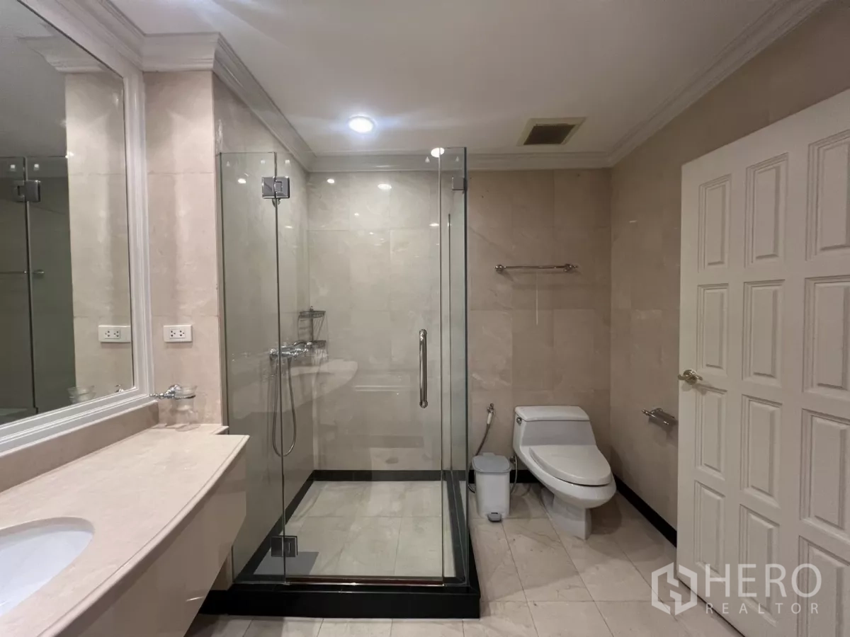 Townhouse for sale in Watthana, Bangkok - Bathroom with glass-enclosed shower, beige tiles and vanity.
