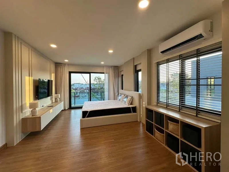 Detached House for rent in Bang Phli, Samut Prakan - Spacious master bedroom with wood floors, balcony access, wide windows, TV wall and air conditioning.