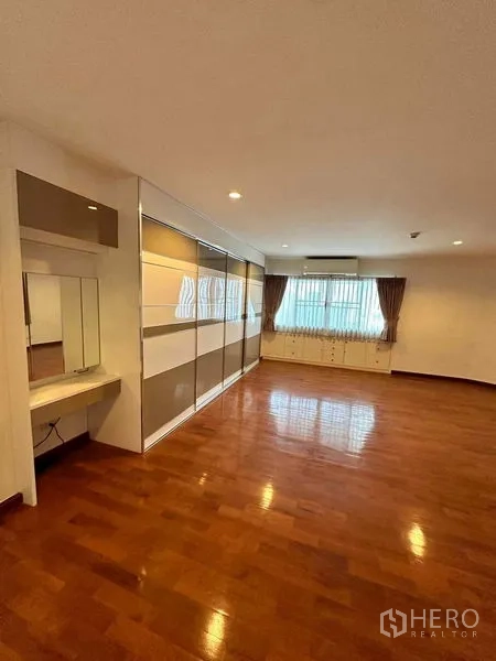 Condominium for rent in Bangkok - Large bedroom with built-in wardrobes, dressing nook and polished wooden floors.