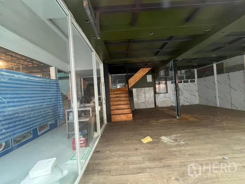 零售空间 出租在Watthana, Bangkok - 开放式零售内部，木楼梯通往夹层，木纹地面。