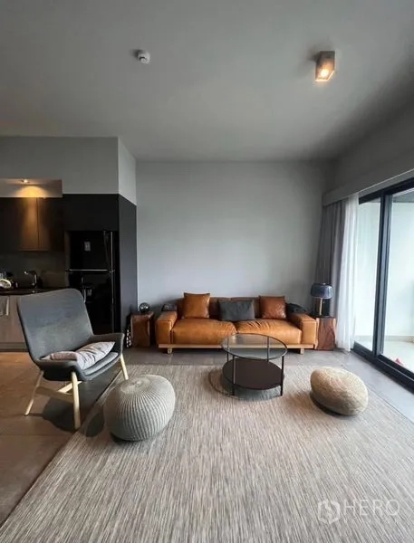 公寓 出租在Watthana, Bangkok - 采光充足的起居区，落地窗、棕色沙发、休闲椅与圆形茶几