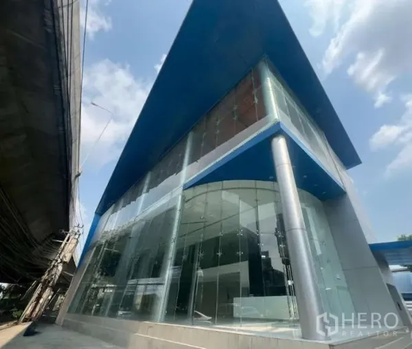 Showroom for rent - Modern glass-fronted showroom exterior with a blue cantilevered roof on a corner site.